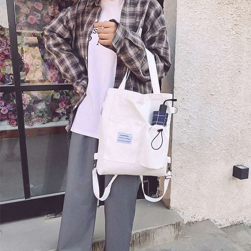 Harajuku style white canvas tote bag with front pockets and accessories, worn with casual outfit