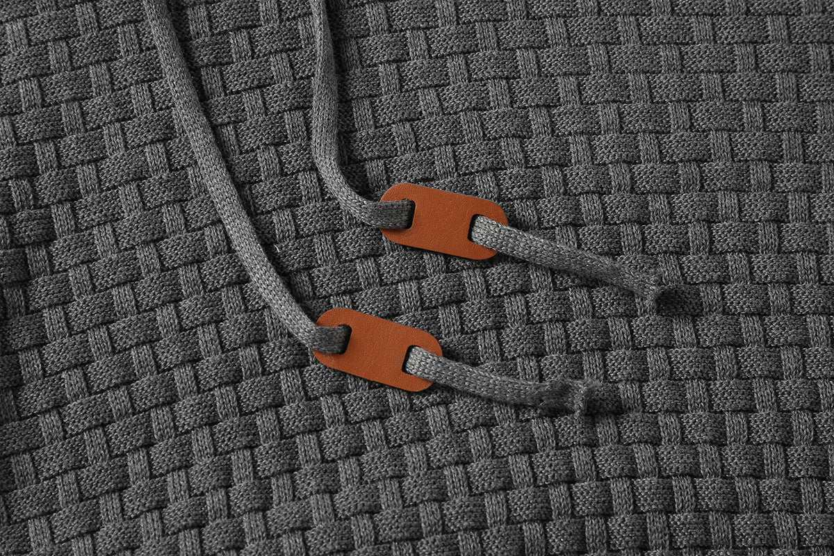 Close-up of grey men's hoodies sweater fabric with woven texture and drawstrings with brown accents