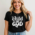 Woman wearing black Child of God T-Shirt with bold white religious typography