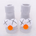 white cotton babysokjes with playful orange and white pom-pom decorations and black crosses