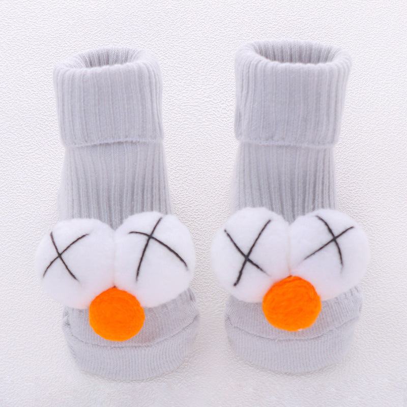 white cotton babysokjes with playful orange and white pom-pom decorations and black crosses