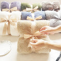 Household simple solid color coral fleece blankets in various colors, neatly folded with ribbons