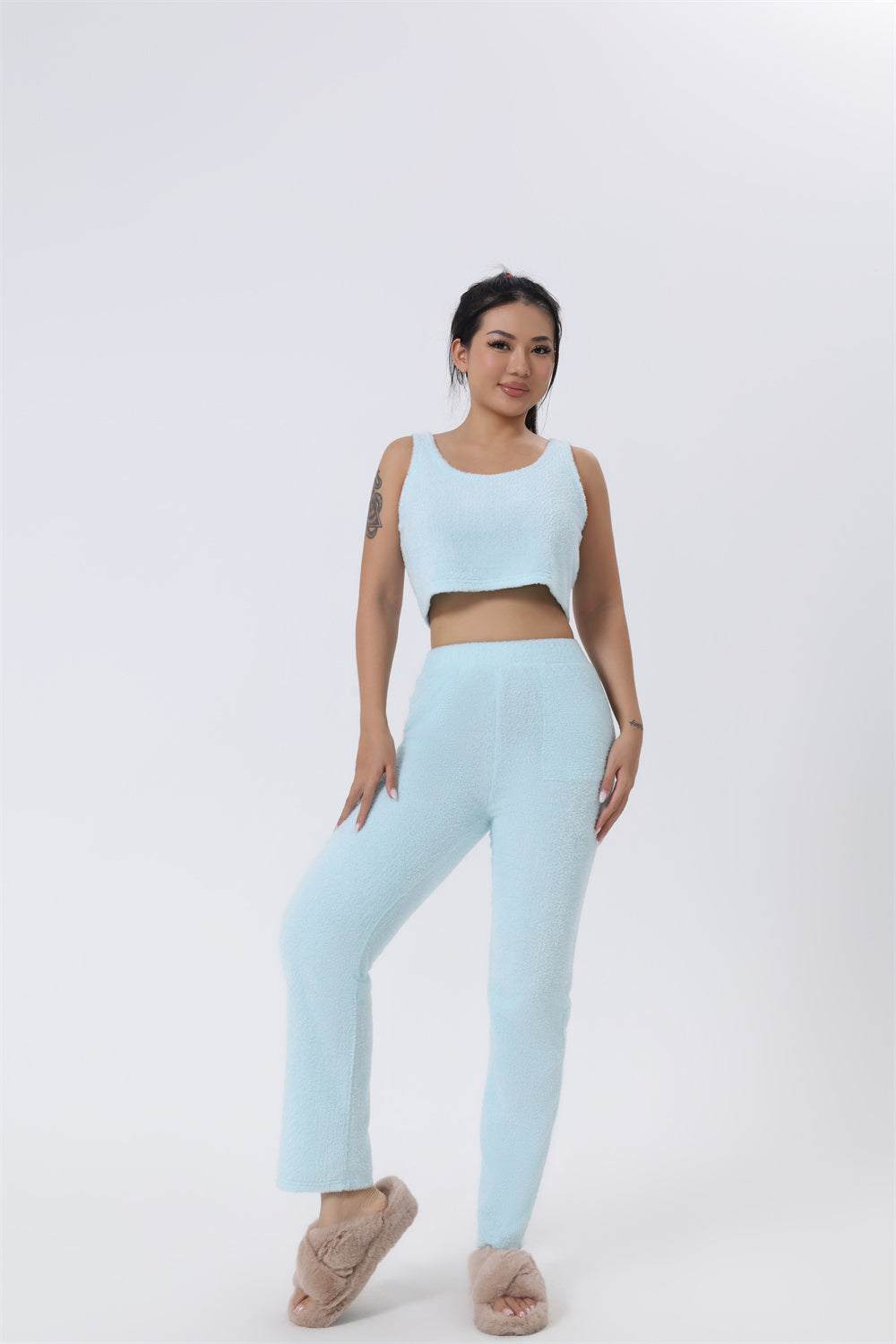 vrouwelijk model in zachte blauwe 3-delige set met crop top en broek