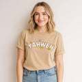 Woman wearing beige YAHWEH Floral Graphic Tee with flower design and blue jeans