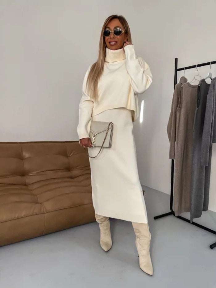 Woman wearing a white turtleneck sweater suit with long sleeveless dress and beige boots.