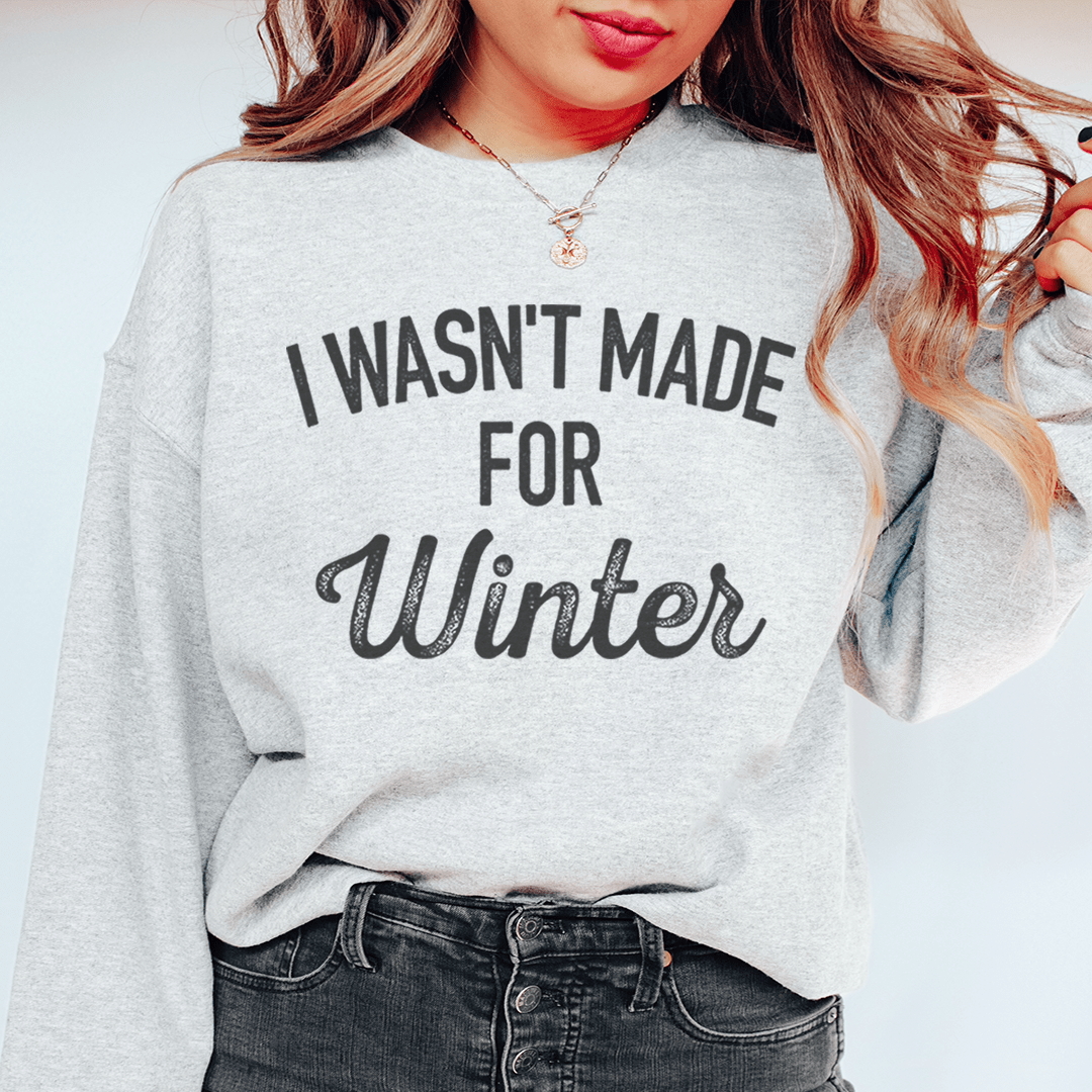 Black "I Wasn't Made For Winter" sweatshirt with cozy fleece lining and adjustable cuffs worn by blonde woman